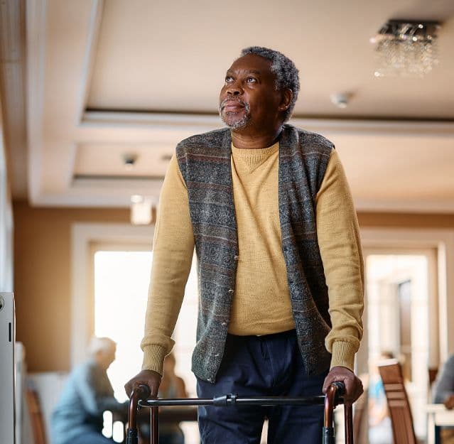 Elderly Black man using a walker for support indoors